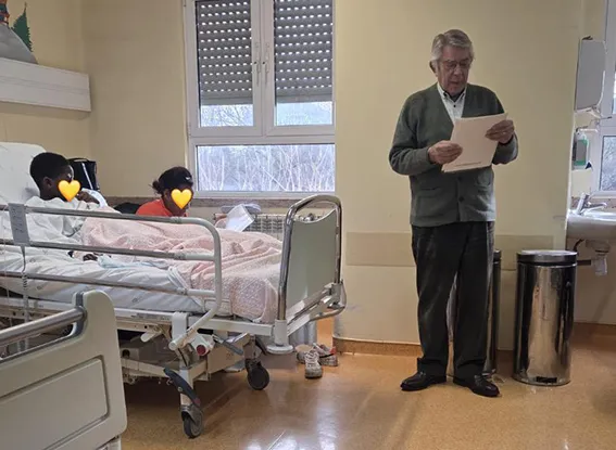 homem conta uma historia a 2 criancas que estao hospitalizadas